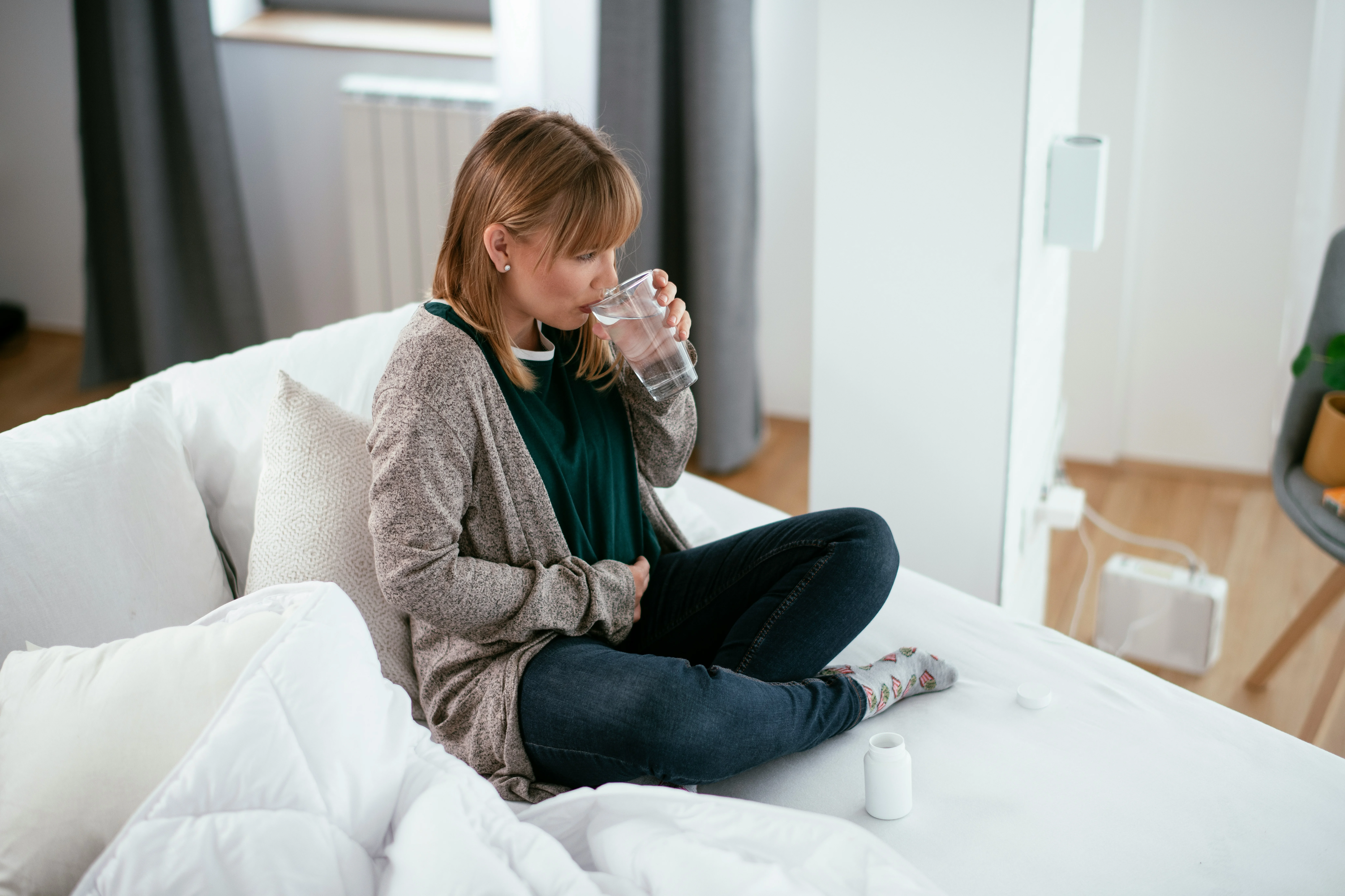 woman drinking water holding her stomach